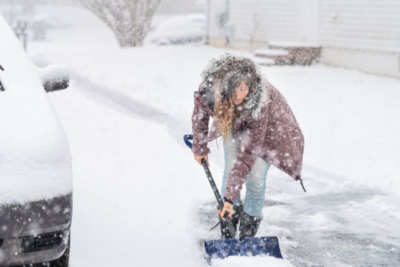 woman shoveling snow in the middle of a snowstorm